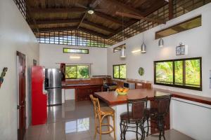 a kitchen with a refrigerator and a table with chairs at Casa de las Palmas, Residencia Isabella in Parrita