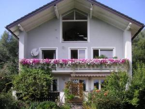 ein weißes Haus mit einem Balkon mit rosa Blumen in der Unterkunft Haus Hillinger in Salzburg