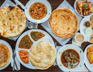 a table topped with plates of food and pies at Amada Family Guest House in Karachi