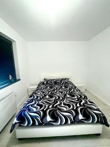 a bed with a black and white blanket on it at Residence 2 in Ploieşti +2 photos