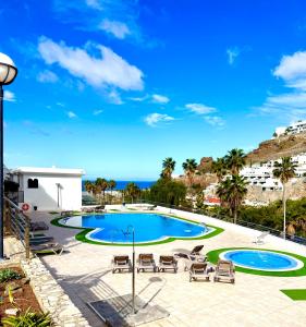 a view of a swimming pool with chairs and the ocean at Miami Beach in Mogán