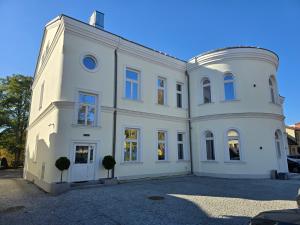 een groot wit gebouw met twee bomen ervoor bij Apartament Pałac Tryllingów in Białystok