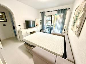 a bed in a room with a couch and a tv at Miami Beach in Mogán