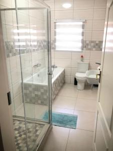 a bathroom with a shower and a tub and a toilet at Divine Boutique Hotel in Rustenburg
