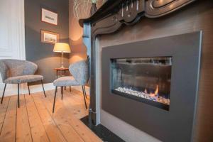 a living room with a fireplace with two chairs and a lamp at Villa Amandine in Ostend
