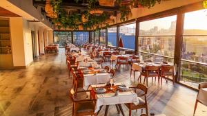 a restaurant with tables and chairs and large windows at Green Park Mardin Hotel 