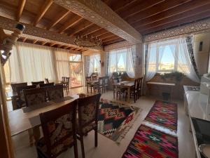 a living room with a table and chairs and windows at NAZIRA Boutique Hotel & Terrace in Khiva