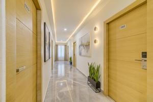 a hallway with wooden doors and a plant at FabHotel Prime Veeraj Suites- Nr Skyview10, Lumbini Avenue, Gachibowli in Hyderabad