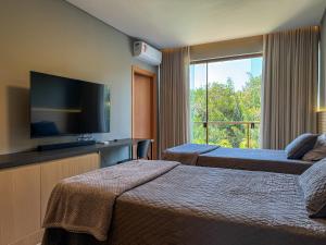 a hotel room with two beds and a flat screen tv at Casa Kuará Praia do Forte in Praia do Forte +23 photos