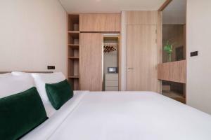 a bedroom with a large white bed with green pillows at Urban Oasis BTS Ekkamai in Khlong Toei