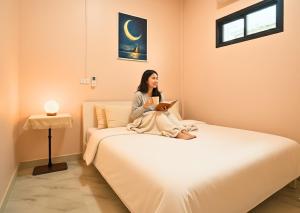 a woman sitting on a bed reading a book at Dalbit Heaven #Patong Beach 3 min walk Super Private House 2BR in Patong Beach