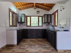 a large kitchen with black and white counters and windows at Shree Dev Asthanam in Bhīm Tāl