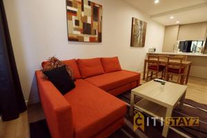 ein Wohnzimmer mit einem orangenen Sofa und einem Tisch in der Unterkunft Ruby Red, 1Bd 1Bth Apt - Woden CBD in Phillip
