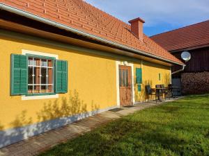 a yellow house with a green window and a table at Klein Poschgan in Leutschach