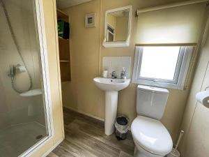a small bathroom with a toilet and a sink at Brilliant 6 Berth Caravan With Decking At Heacham Beach Park Ref 21031A in Heacham +13 photos