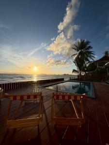 deux chaises assises à côté d'une piscine au bord de l'océan dans l'établissement Bliss Resort Krabi, à Klong Muang Beach