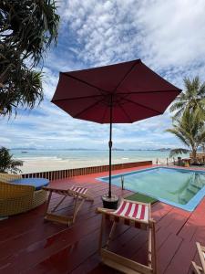 un parasol rouge assis sur une terrasse à côté d'une piscine dans l'établissement Bliss Resort Krabi, à Klong Muang Beach