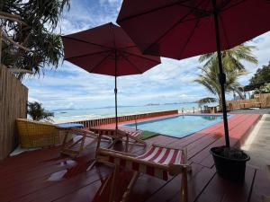 a deck with chairs and umbrellas and a swimming pool at Bliss Resort Krabi in Klong Muang Beach