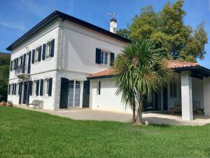 un bâtiment blanc avec un palmier devant dans l'établissement Maison idéale à Mendionde pour 8 personnes, avec grand jardin et équipements modernes - FR-1-495-104, à Mendionde