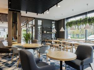 a restaurant with tables and chairs and windows at ibis Styles Kraków East in Kraków