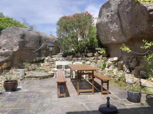 a wooden table and benches in a garden with rocks at Maison de vacances 3 étoiles avec jardin à Trégastel, proche plage - FR-1-542-62 in Trégastel