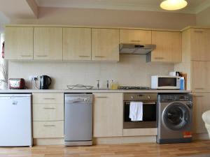 a kitchen with a washing machine and a microwave at Jasmine Cottage in Knitsley