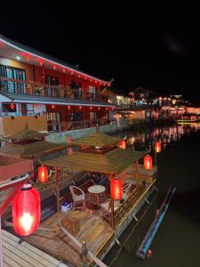 Un muelle con un restaurante y farolillos rojos en el agua. en ริมหมอก จาต๋ารักไทย, en Ban Rak Thai 11 fotos más
