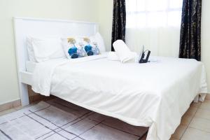 a white bed with a white bedspread on it at Solace Park Apartments in Gatunga
