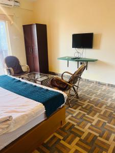 een kamer met een bed, een bureau en een televisie bij Hotel Anandam Elegance in Morjim