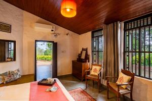a living room with a table and chairs and windows at Jade Hills Coorg in Madikeri
