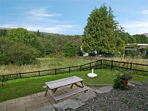a wooden picnic table in a yard with a fence at Lockside Lower Flat in Fort Augustus