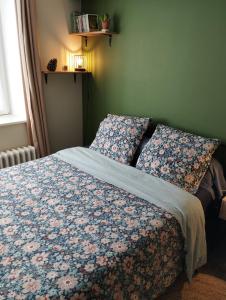 a bedroom with a bed with a floral bedspread and pillows at À fleur de source in Mer