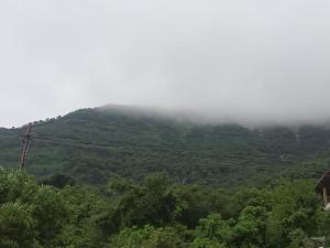 a view of a mountain with clouds in the sky at Girijalsrushti Pool Villa in Kolvan
