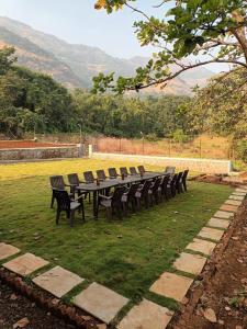 una mesa larga con sillas sobre el césped en Girijalsrushti Mountain Stream View Villa, en Kolvan