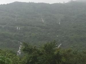 a view of a mountain with trees and power lines at Girijalsrushti Pool Villa in Kolvan