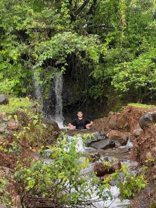a man sitting in front of a waterfall at Girijalsrushti Pool Villa in Kolvan
