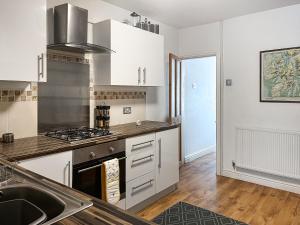 una cucina con mobili bianchi e una stufa di Miner's Rest a Rowrah