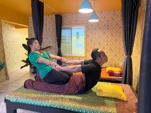 two people sitting on a bed in a room at Dengba Hostel - Loikroh Chiangmai in Ban Hua Phrong