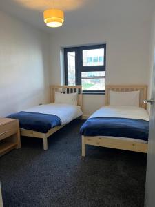 two beds in a room with a window at The Homely Retreat Spacious Ground Floor Flat Near Oxford City Centre, Free Parking in Oxford