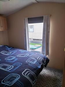 a bedroom with a bed and a window with a view at Willows 104 Caravan - 7 Lakes in Crowle