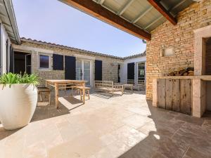 d'une terrasse avec une table et des bancs et un mur en briques. dans l'établissement Maison 5 chambres jusqu'à 10 pers - Proche Phare des Baleines - FR-1-835-17, à Saint-Clément-des-Baleines