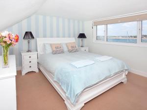 a white bedroom with a bed and a window at Shorewaters in Appledore
