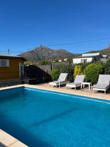 a swimming pool with two lounge chairs next to a house at Cabaña Paz in Capilla del Monte +23 photos