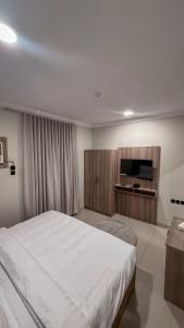 a bedroom with a large white bed and a television at زهرة القصيم شقق مفروشة in Buraydah +28 photos