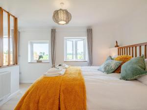 a bedroom with a large bed with an orange blanket at Cosyleigh in Stalham