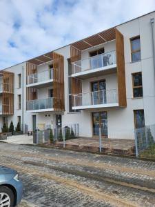 een appartementencomplex met balkons en een auto aan de voorzijde bij Apartament Jagiełly in Olsztynek