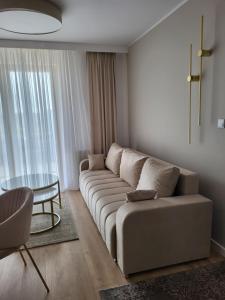 een woonkamer met een bank en een glazen tafel bij Apartament Jagiełly in Olsztynek