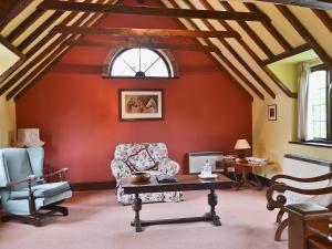 a living room with red walls and a table and chairs at Mill Cottage in Mathon