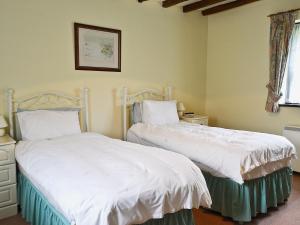 two beds sitting next to each other in a bedroom at Mill Cottage in Mathon +2 photos