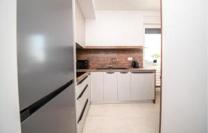 Una cocina con gabinetes blancos y un refrigerador de acero inoxidable. en Lovely Apartment In Vrsi With Sauna, en Kod Mula